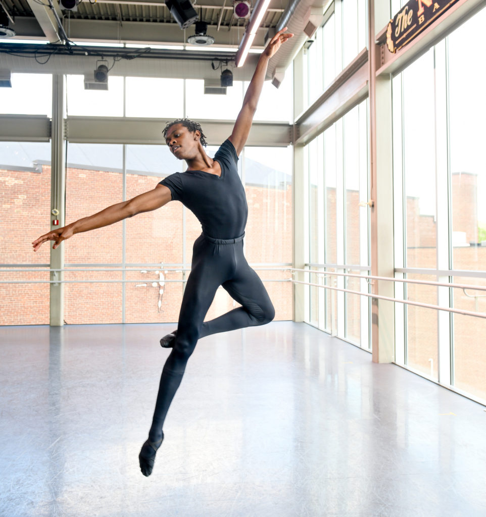 A Black young man midair in a sauté passé