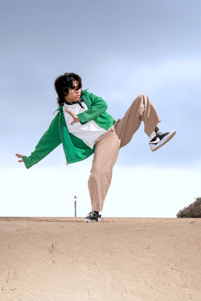 Gabe De Guzman poses outside. He lifts one knee as he leans opposite ways. 