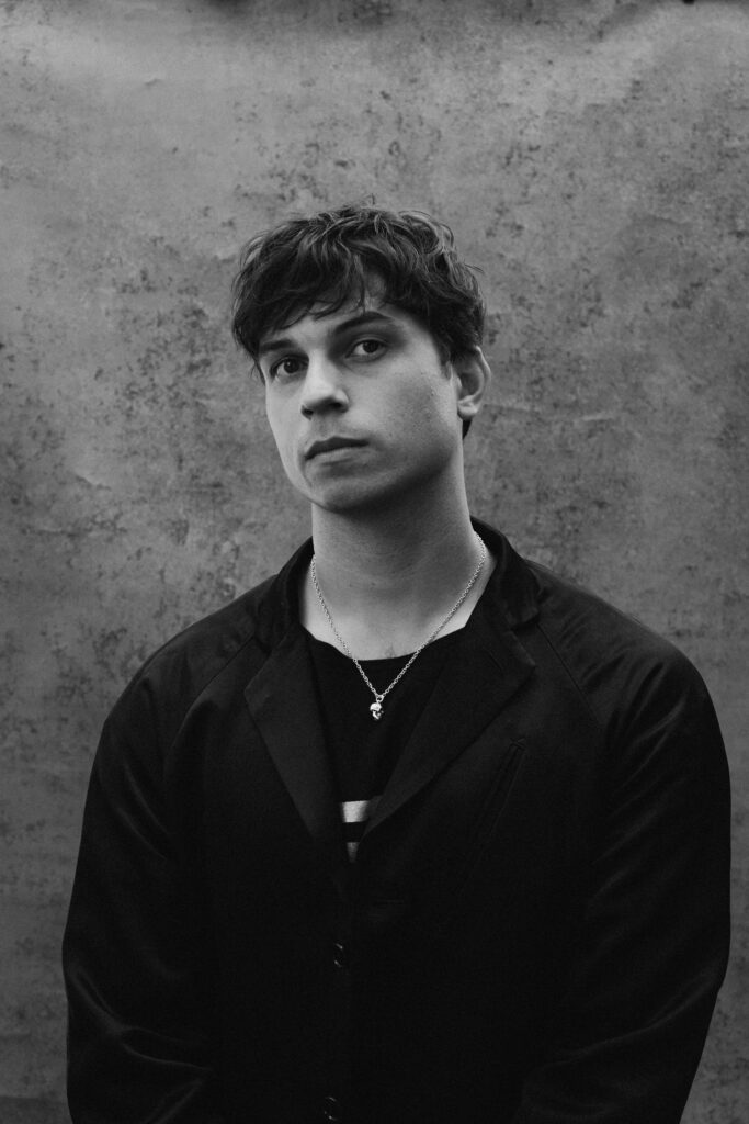 Corey Baker poses for a black-and-white portrait wearing a dark button-down.